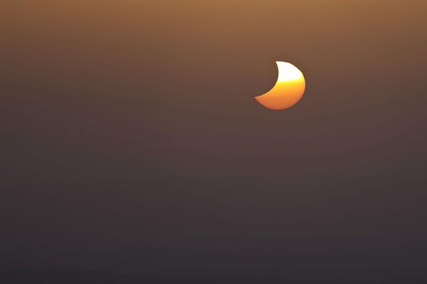 Moon eclipsing the sun as its drops into the Granada heat haze