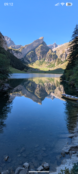 Reflection of a mountaintop in a lake's flat water surface on a sunny day.