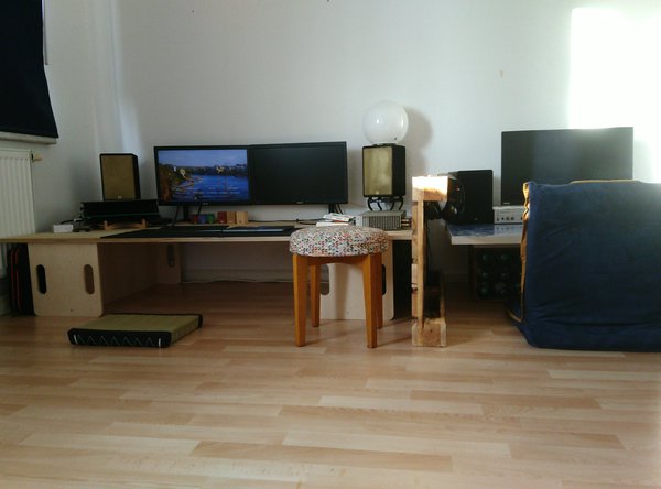 Bodenschreibtische, links 189cm Länge, auf zwei Kindersitzbänken liegend, mit zwei großen Monitoren und zwei Notebooks ausgestattet. Rechts 150cm, mit einem großen Monitor und einem MacBook, was damals meine Arbeitsausrüstung war.