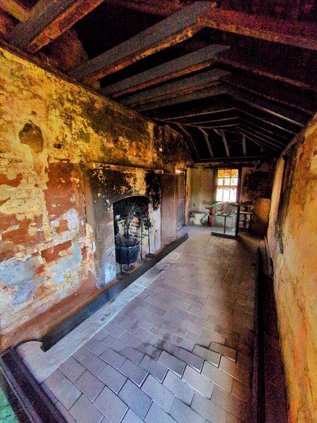 The front room. There's a fireplace covered in soot, most of the render has peeled off the walls, and the dark timber roof has blackened.